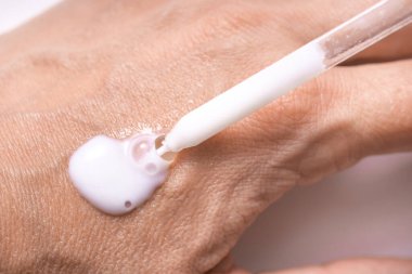 Kadın eline pipetle kozmetik serum kremi sür