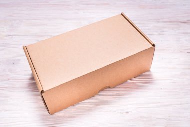 Kahverengi karton düz posta kutusu, çanta, ahşap masa.