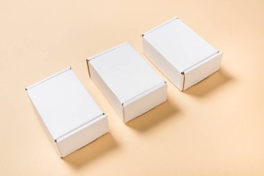 Üç beyaz karton, bej sırt çantalı düz posta kutusu.