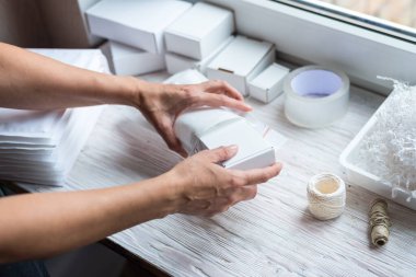 Kadın elleri karton kutu ve karton posta zarfıyla çalışıyor.