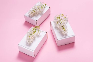 Pembe perde arkasında leylak çiçeklerle süslenmiş hediye kutuları.