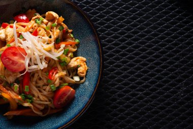 Siyah tabakta tavuk ve sebzeli erişte ve Spac fotokopisi.