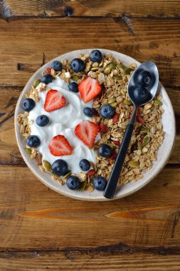 Çilek ve kahverengi bir arka plan üzerinde yaban mersini ile müsli