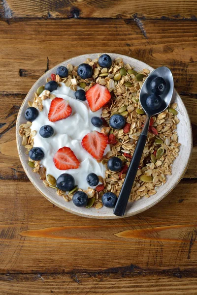 Çilek ve kahverengi bir arka plan üzerinde yaban mersini ile müsli