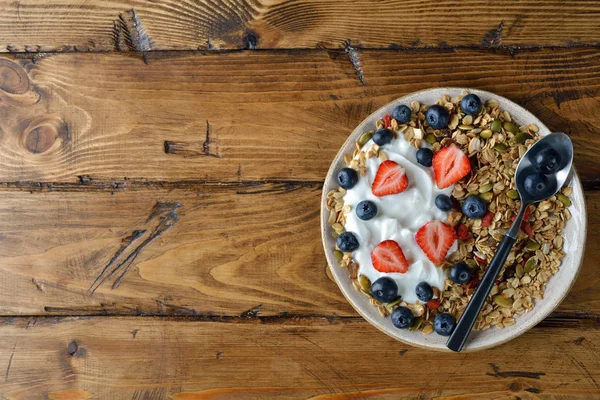 Çilek ve kahverengi bir arka plan üzerinde yaban mersini ile müsli