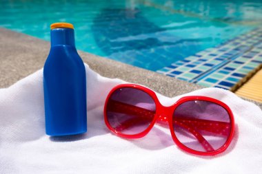 Yüzme Havuzu arka planda kırmızı Sunglass ve güneş bloğu şişe