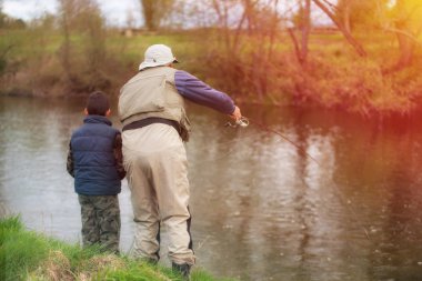 Baba ve oğul sonbahar sezonu gün batımında Nehirde balık tutma