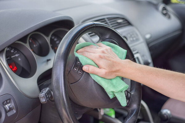 Young woman cleaning car interior with microfiber cloth. Car detailing.