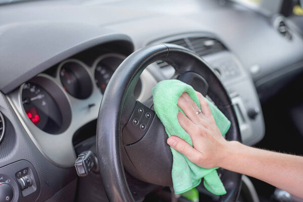 Young woman cleaning car interior with microfiber cloth. Car detailing.