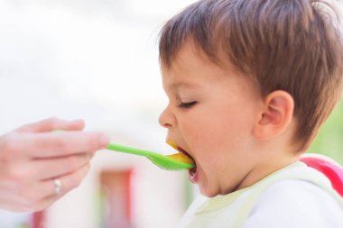 Smartphone vasıl ararken öğle yemeği yiyen bebek