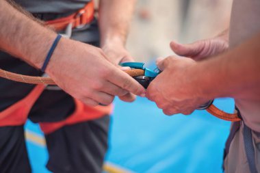 Rock wall climber wearing safety harness and climbing equipment indoor, close-up image clipart