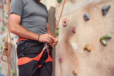 Emniyet kemeri takıyor ve ekipman kapalı, yakın çekim görüntü tırmanma duvarı dağcı