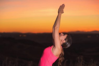 Gün batımında yoga yapan genç ve güzel bir kadın.
