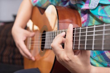 Sakallı hippi adam el akustik gitar çalmak. Yakın çekim seçici odak üstünde el.