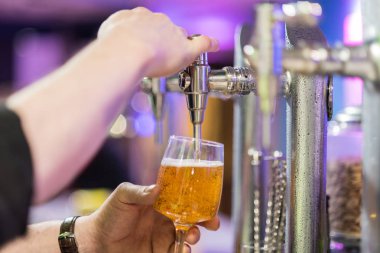 Barmen bir cam Lager Bira döküyor. Sığ dof, seçici odak.