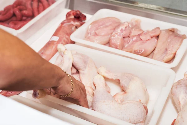Butcher serving fresh chicken meat at display in butchery