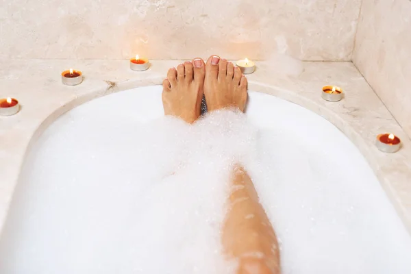 Woman legs in bath foam. Relaxation in spa.