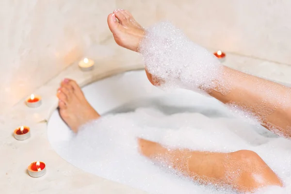 Woman legs in bath foam. Relaxation in spa.