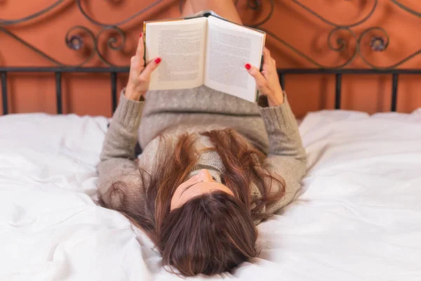 Žena ležela v posteli s knihou — Stock fotografie
