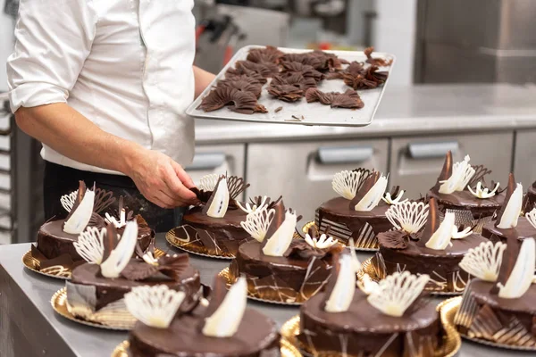 Pastry Chef decorating chocolate cakes in the kitchen of pastry shop