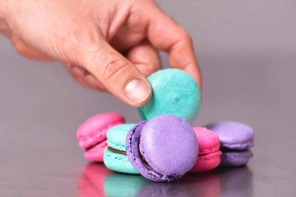 Faça mão pegando um macaron na mesa — Fotografia de Stock