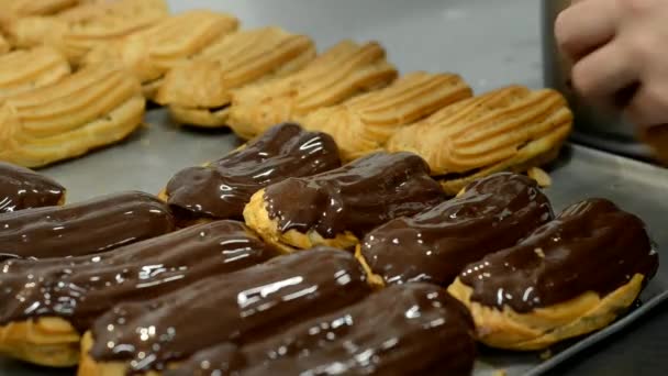 Banketbakker productie. Gieten van gesmolten chocolade op Eclair of profiterol. — Stockvideo