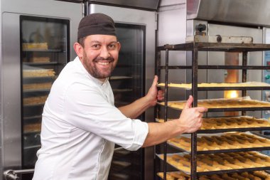 Baker ekmek veya pasta dükkanı fırında hamur işleri bir rafa koyarak.