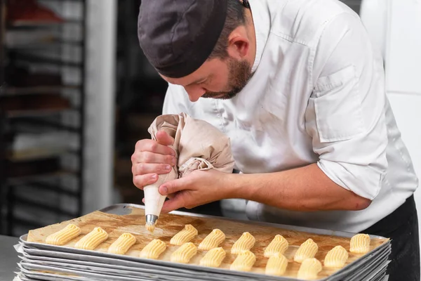 Pastry Chef with confectionary bag squeezing cream at pastry shop.