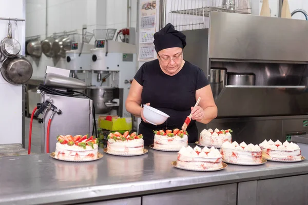 Woman pastry chef smiling and working happy, making cakes at the pastry shop.