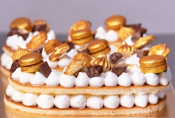 Delicious cream cake decorated with golden sweets. — Stock Photo, Image