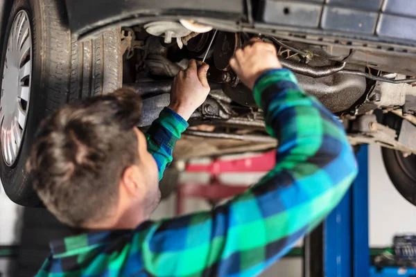 Retrato de mecánico reparando con una llave un coche levantado . — Foto de Stock