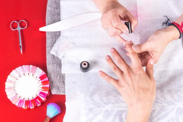 Mesa de trabajo de manicura profesional con herramientas de trabajo, aplicando esmalte de uñas en un salón de uñas de mujer . — Foto de Stock
