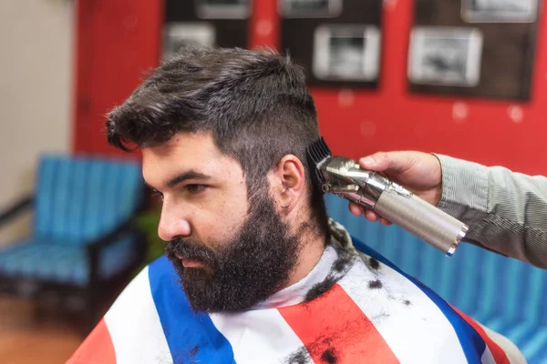 在理发店由理发师理发的英俊的英俊的胡须的男人. — 图库照片