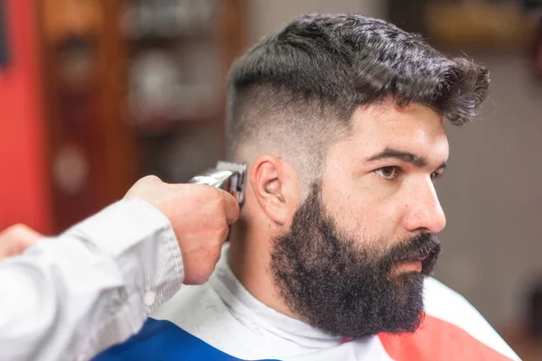 英俊的胡须男子, 得到理发师理发, 在理发店的电动修剪器. — 图库照片