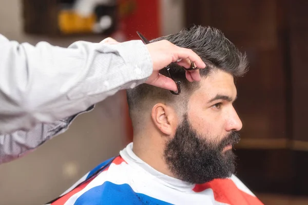 Knappe bebaarde man, die haar gesneden door de schaar op Kapper. — Stockfoto