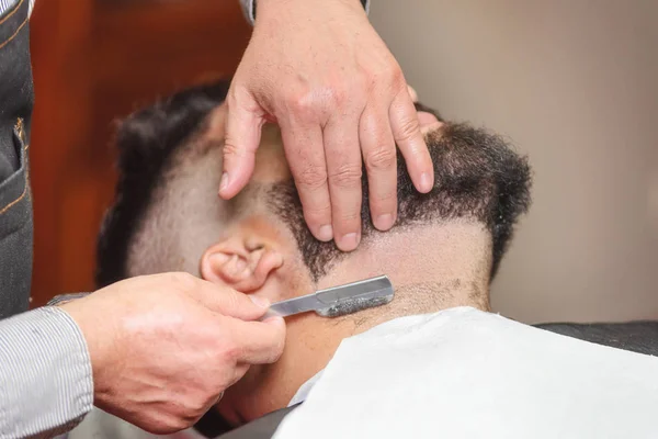 Knappe man met een scheerbeurt met vintage scheermes in de barbershop. — Stockfoto