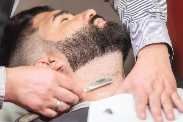 Knappe man met een scheerbeurt met vintage scheermes in de barbershop. — Stockfoto
