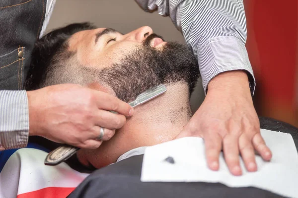 Knappe man met een scheerbeurt met vintage scheermes in de barbershop. — Stockfoto