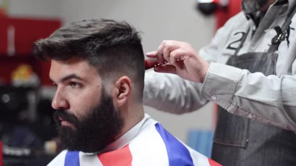 Hombre barbudo guapo consiguiendo corte de pelo por peluquería en la peluquería . — Vídeo de stock