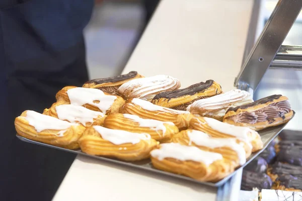 Tray of eclairs on pastry shop counter.