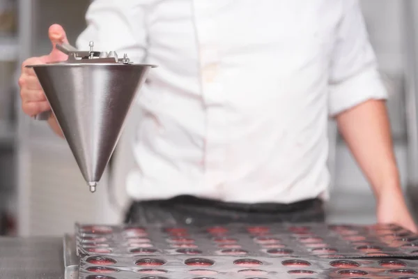 Pastry chef pouring strawberry marmalade, working at kitchen of pastry shop.