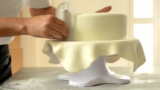 Кондитер украшает свадебный торт белой помадкой. — стоковое видео