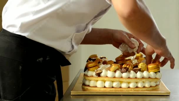 Кондитер украшает вкусный торт с золотыми сладостями . — стоковое видео