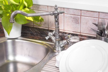 Rustik metal evye üzerinde temiz bulaşıkları kurutma.