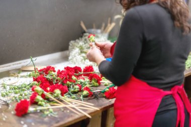 Kadın Çiçekçi Çiçek dükkanında güzel kırmızı karanfil buketi oluşturma, yakın çekim.