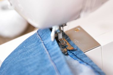 Sewing denim jeans with sewing machine. Repair jeans by sewing machine. clipart