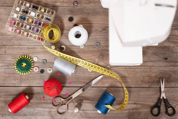 Seamstress or tailor background top view with sewing tools, colorful threads, sewing machine and accesories .