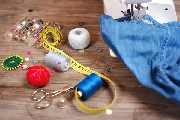 Seamstress or tailor background top view with jeans, sewing tools, colorful threads, sewing machine and accesories . — Stock Photo, Image