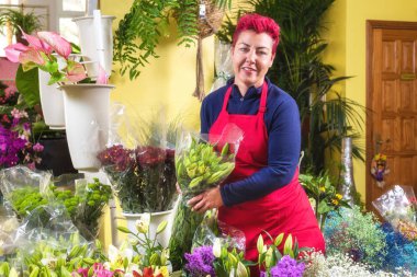 Mutlu kadın çiçekçi, düzenlemeler yapma ve kameraya gülümseyerek. küçük işletme Çiçekçi dükkanı sahibi.