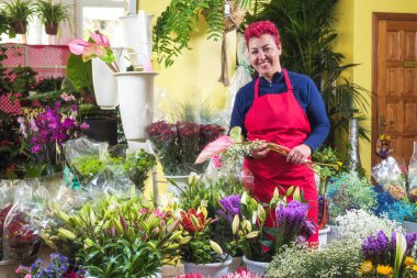 Mutlu kadın çiçekçi, düzenlemeler yapma ve kameraya gülümseyerek. küçük işletme Çiçekçi dükkanı sahibi.
